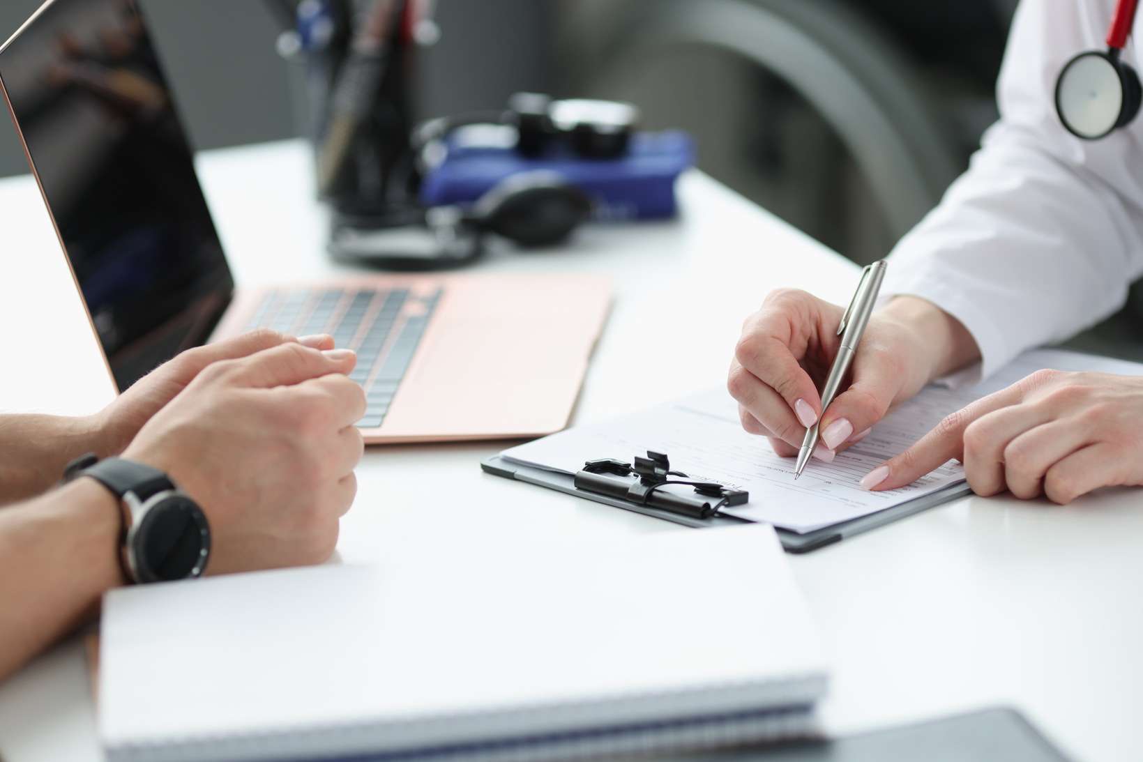 Doctors hands writing down patients complaints in medical history closeup